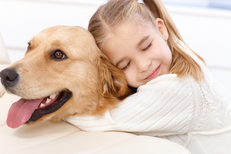 A child hugging a golden retriever